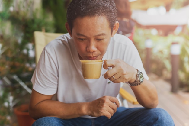 Hombre caucásico en jean y camiseta blanca bebiendo café en la cafetería