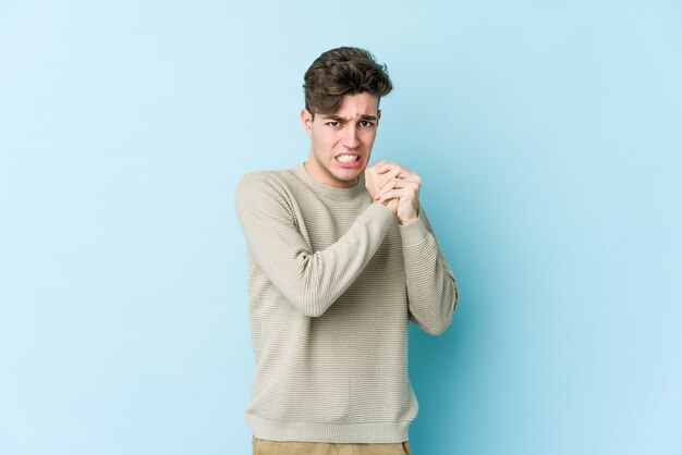 Hombre caucásico joven aislado en la pared azul asustado y asustado.