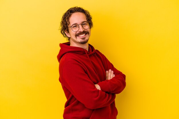 Hombre caucásico joven aislado sobre fondo amarillo feliz, sonriente y alegre.