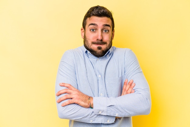 Hombre caucásico joven aislado sobre fondo amarillo sopla mejillas tiene expresión cansada Concepto de expresión facial