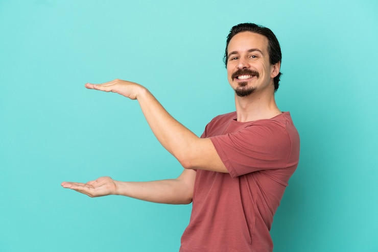 Foto hombre caucásico joven aislado sobre fondo azul con copyspace para insertar un anuncio