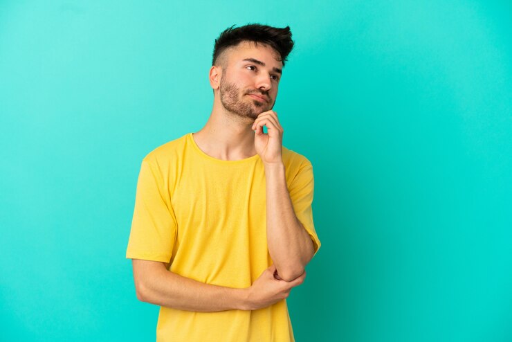 Foto hombre caucásico joven aislado sobre fondo azul con dudas y pensamiento