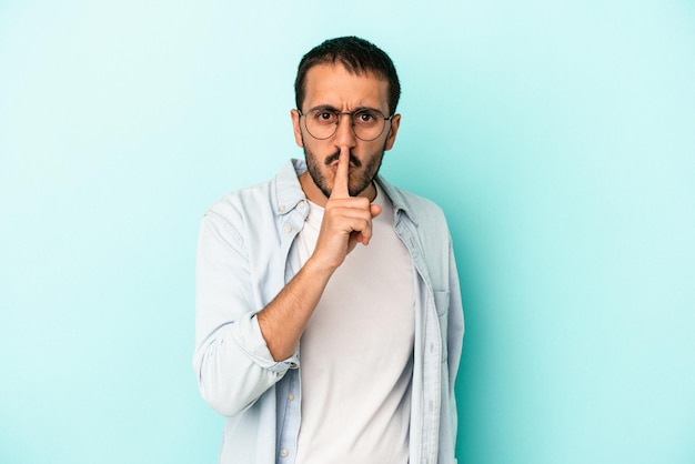 Hombre caucásico joven aislado sobre fondo azul manteniendo un secreto o pidiendo silencio.