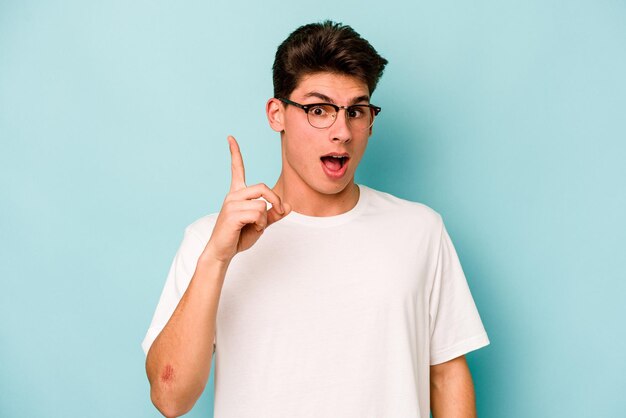 Hombre caucásico joven aislado sobre fondo azul que tiene un concepto de inspiración de idea