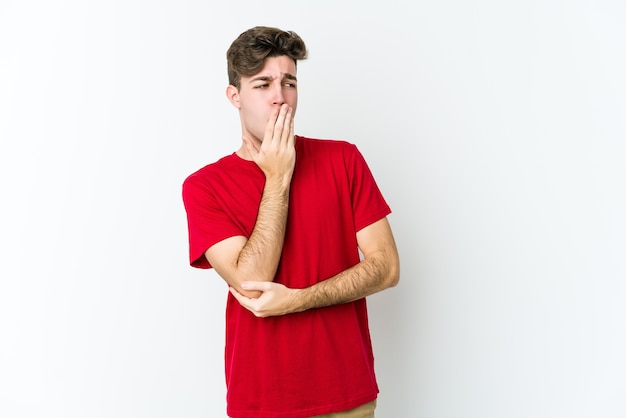 Hombre caucásico joven aislado sobre fondo blanco bostezando mostrando un gesto cansado cubriendo la boca con la mano.