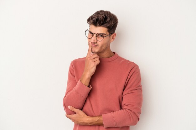 Hombre caucásico joven aislado sobre fondo blanco contemplando, planificando una estrategia, pensando en la forma de un negocio.