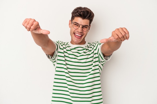 Hombre caucásico joven aislado sobre fondo blanco levantando ambos pulgares, sonriente y confiado.