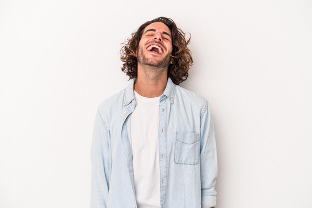 Hombre caucásico joven aislado sobre fondo blanco relajado y feliz riendo, cuello estirado mostrando los dientes.