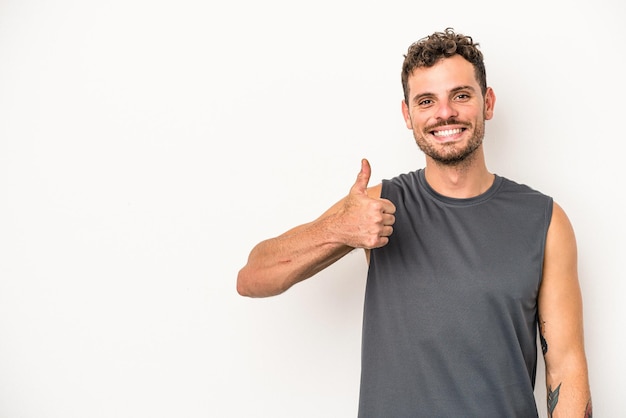 Foto hombre caucásico joven aislado sobre fondo blanco sonriendo y levantando el pulgar