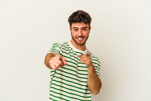 Hombre caucásico joven aislado sobre fondo blanco sonrisas alegres apuntando al frente.