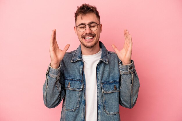 Hombre caucásico joven aislado sobre fondo rosa alegre riendo mucho. concepto de felicidad.