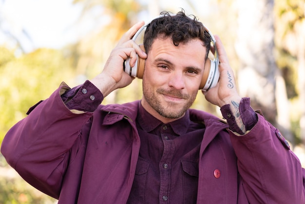 Hombre caucásico joven al aire libre escuchando música