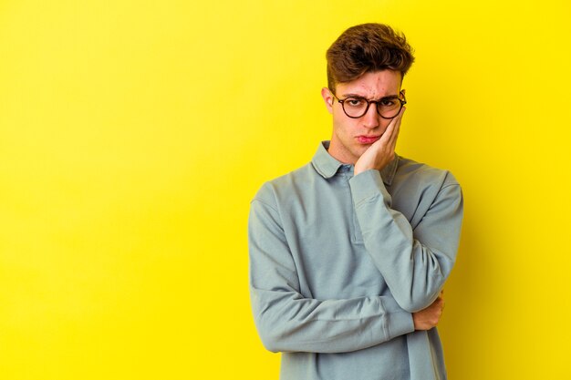 Hombre caucásico joven en amarillo que se siente triste y pensativo, mirando el espacio de la copia.