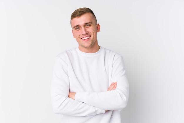 Hombre caucásico joven en blanco que se siente seguro, cruzando los brazos con determinación.