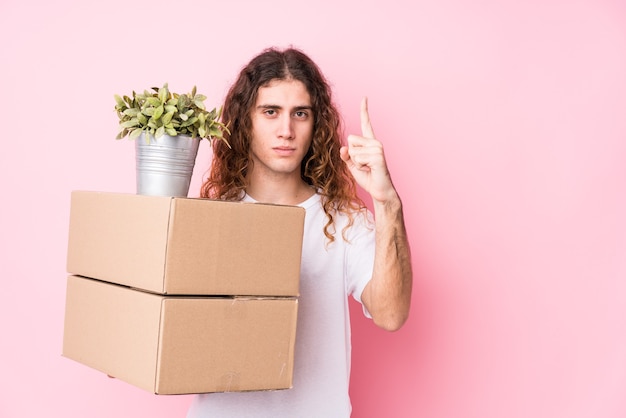 Hombre caucásico joven con cajas aisladas mostrando el número uno con el dedo.