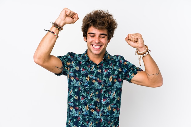 Hombre caucásico joven con una camiseta de flores aislada celebrando un día especial, salta y levanta los brazos con energía.