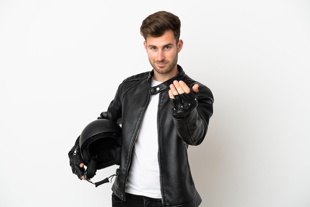 Hombre caucásico joven con un casco de moto aislado sobre fondo blanco que invita a venir con la mano. feliz de que hayas venido