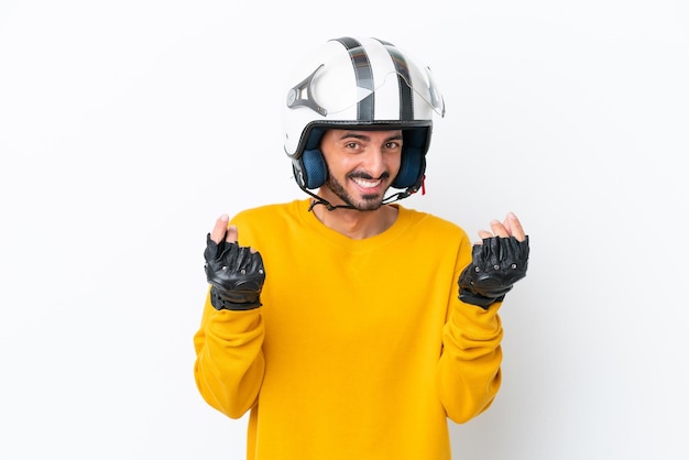 Hombre caucásico joven con un casco de motocicleta aislado sobre fondo blanco haciendo gesto de dinero