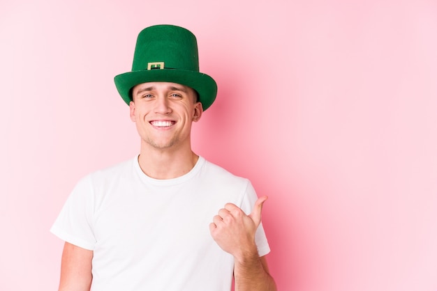 Hombre caucásico joven celebrando el día de San Patricio sonriendo y levantando el pulgar hacia arriba