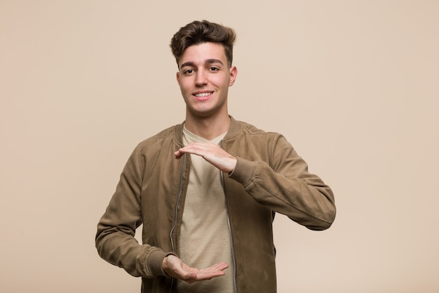 Hombre caucásico joven con una chaqueta marrón sosteniendo algo con ambas manos, presentación del producto.