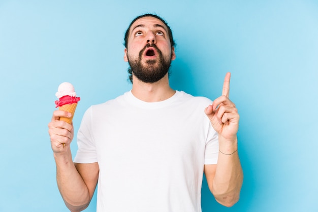 Hombre caucásico joven comiendo un helado apuntando al revés con la boca abierta.