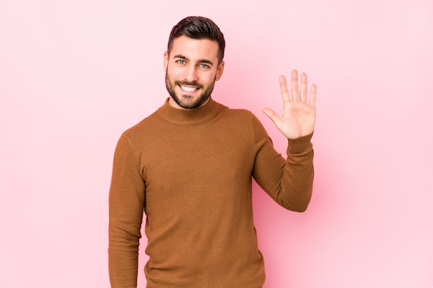 Hombre caucásico joven contra un rosa aislado sonriente alegre que muestra el número cinco con los dedos.