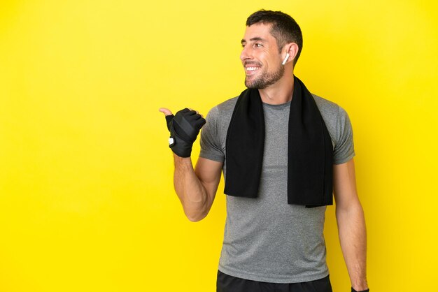 Foto hombre caucásico joven deporte aislado sobre fondo amarillo apuntando hacia el lado para presentar un producto