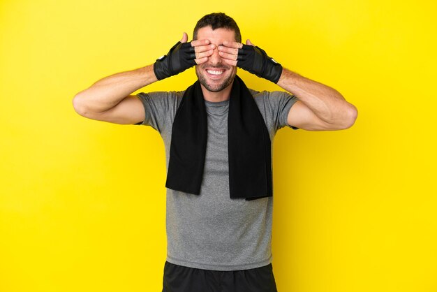 Hombre caucásico joven deporte aislado sobre fondo amarillo que cubre los ojos con las manos