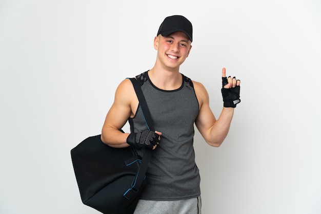 Hombre caucásico joven deporte con bolsa aislado sobre fondo blanco apuntando hacia una gran idea