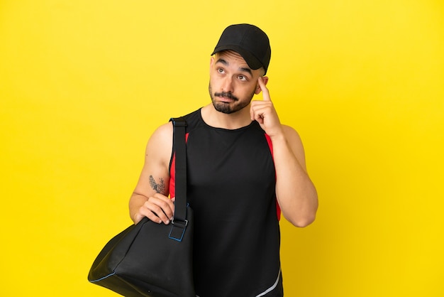 Hombre caucásico joven deporte con bolsa de deporte aislado sobre fondo amarillo pensando en una idea