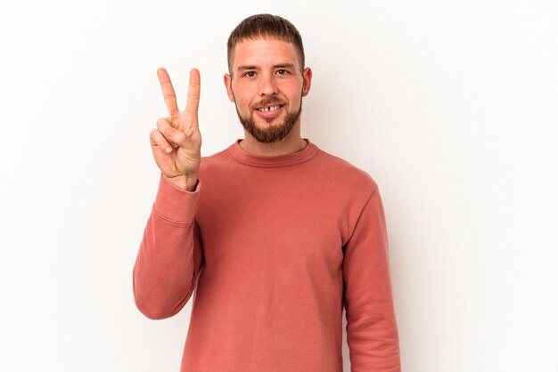 Hombre caucásico joven con diastema aislado sobre fondo blanco que muestra el número dos con los dedos.