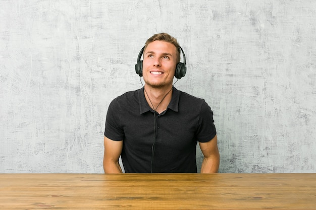 Hombre caucásico joven escuchando música con auriculares soñando con lograr objetivos y propósitos