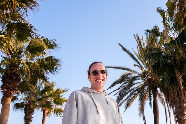 Hombre caucásico joven con gafas de sol sonriendo feliz