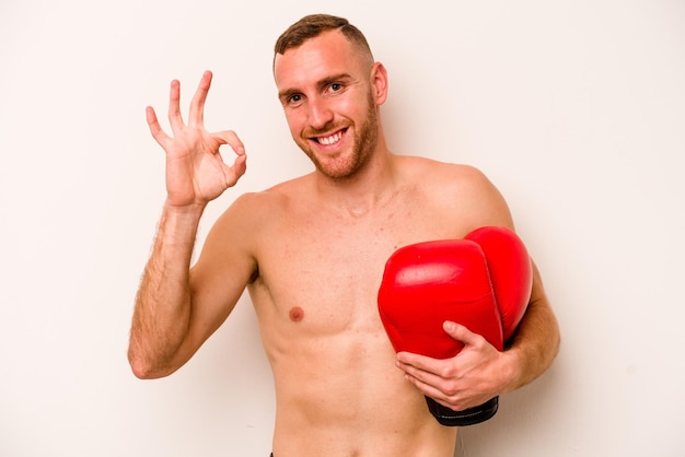 Hombre caucásico joven haciendo boxeo aislado sobre fondo blanco alegre y confiado mostrando gesto ok