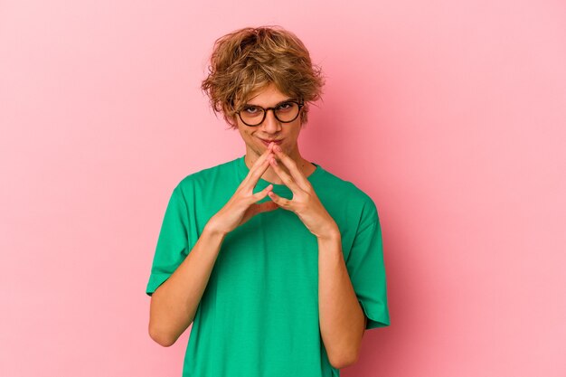 Hombre caucásico joven con maquillaje aislado sobre fondo rosa haciendo un plan en mente, creando una idea.