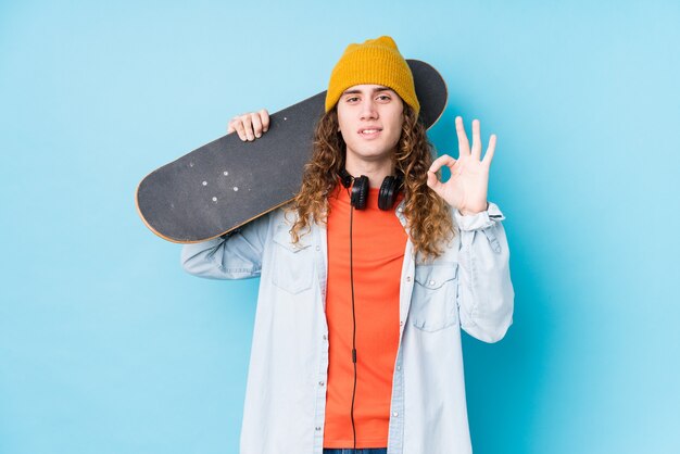 Hombre caucásico joven del patinador aislado alegre y confiado que muestra el gesto aceptable.