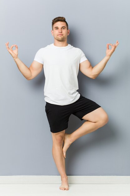 Hombre caucásico joven practicando yoga interior