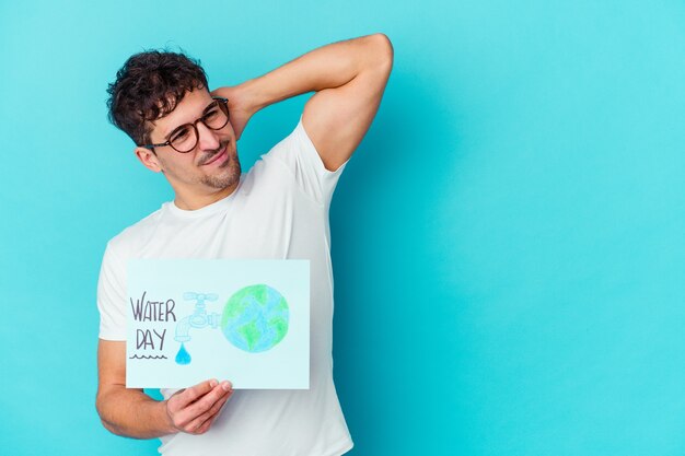 Hombre caucásico joven que celebra el día mundial del agua aislado tocando la parte posterior de la cabeza, pensando y haciendo una elección.