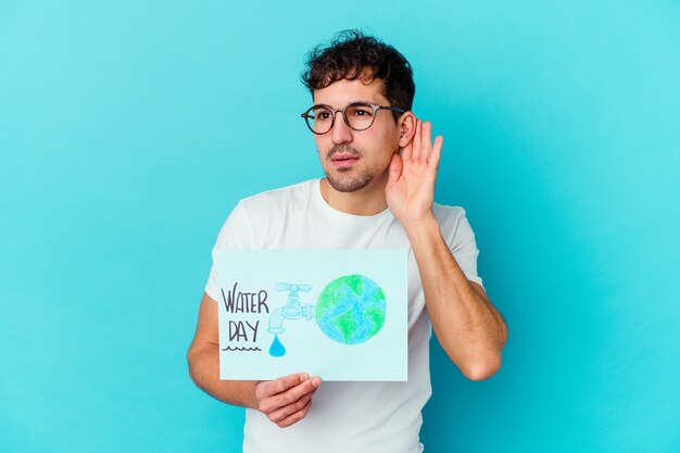 Hombre caucásico joven que celebra el día mundial del agua aislado tratando de escuchar un chisme.