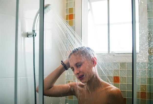 Hombre caucásico joven que se ducha en cuarto de baño