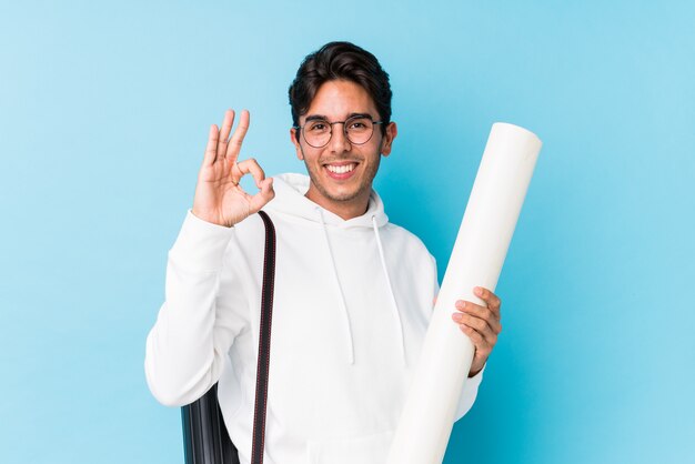 Hombre caucásico joven que estudia la arquitectura alegre y confiada que muestra gesto aceptable.