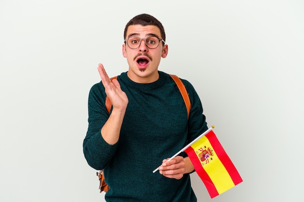 Hombre caucásico joven que estudia inglés aislado en el fondo blanco sorprendido y consternado.