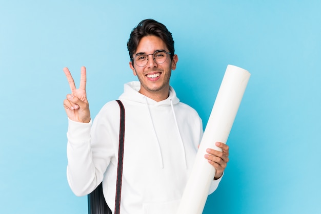 El hombre caucásico joven que estudiaba la arquitectura aisló alegre y despreocupado que mostraba un símbolo de paz con los dedos.