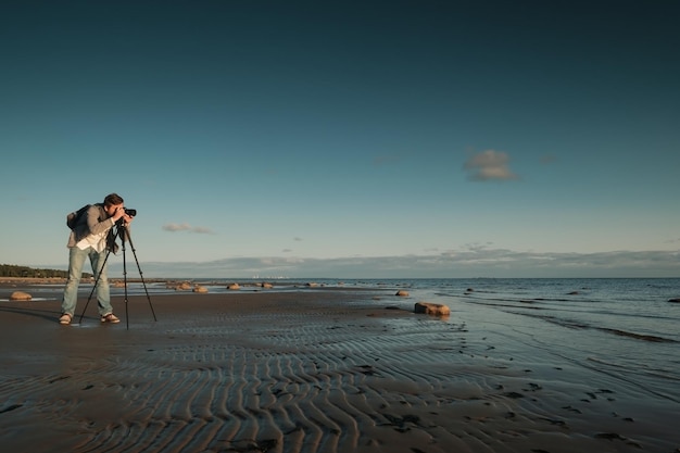 Hombre caucásico joven que hace la foto del paisaje en la playa