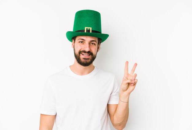 El hombre caucásico joven que llevaba un sombrero de San Patricio aisló alegre y despreocupado mostrando un símbolo de paz con los dedos.