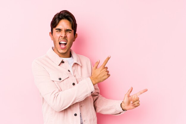Hombre caucásico joven que presenta en señalar aislado rosado con los dedos índices a un espacio de la copia, expresando la emoción y el deseo.