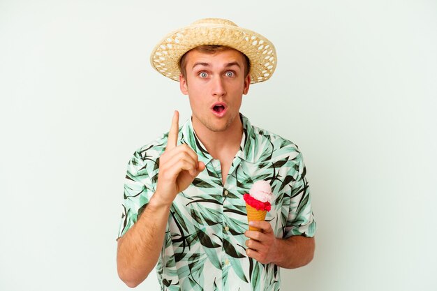 Hombre caucásico joven con ropa de verano y sosteniendo un helado aislado sobre fondo blanco con una idea, concepto de inspiración.