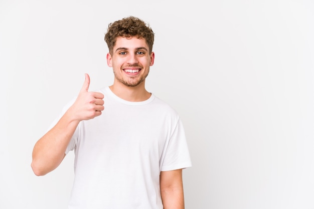 Hombre caucásico joven rubio del pelo rizado aislado sonriendo y levantando el pulgar para arriba