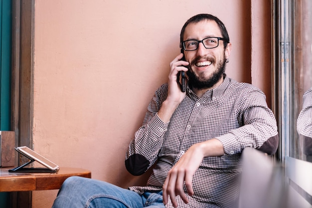 Hombre caucásico joven sonriendo feliz hablando en el teléfono inteligente