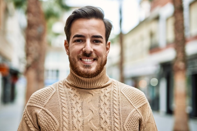 Hombre caucásico joven sonriendo feliz de pie en la ciudad.